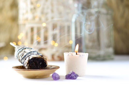 Sage burning near amethyst crystals and a candle.