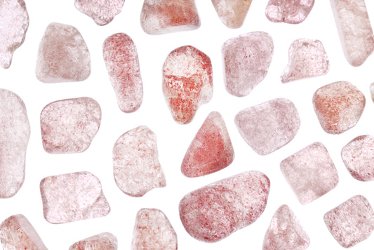 many strawberry quartz crystals laid out on a white background