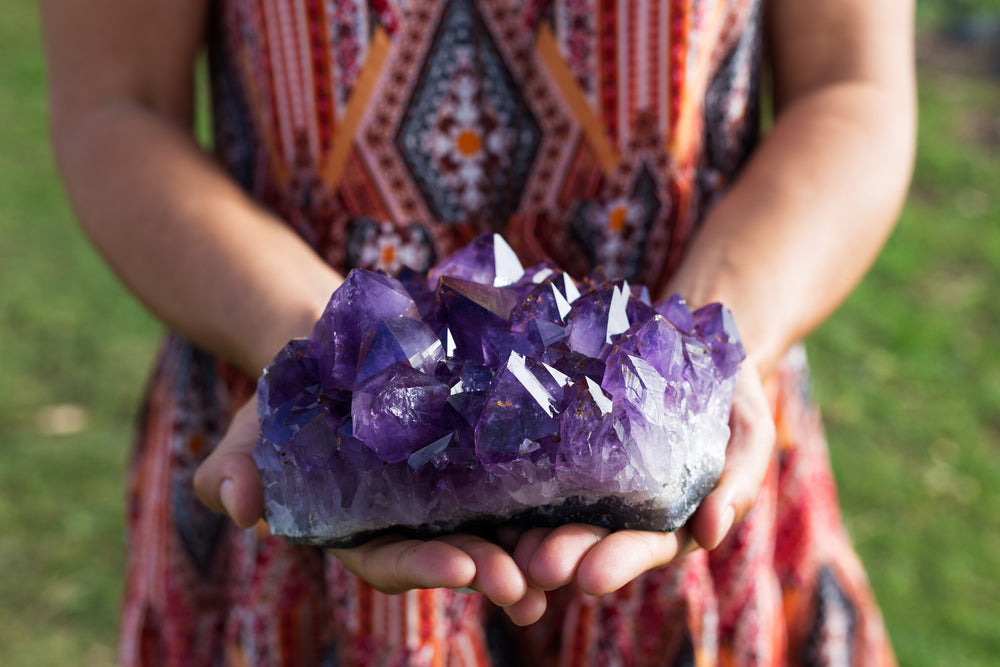 Woman holding large amethyst cluster crystal.